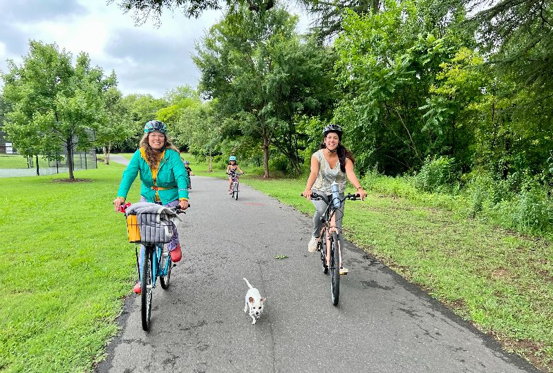 2 People Biking on Greenway with Dog