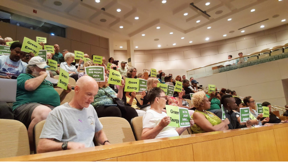 City council meeting with Green Energy protest signs