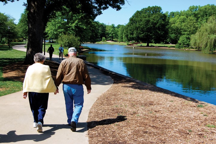 Older Couple walks along a sunny greenway