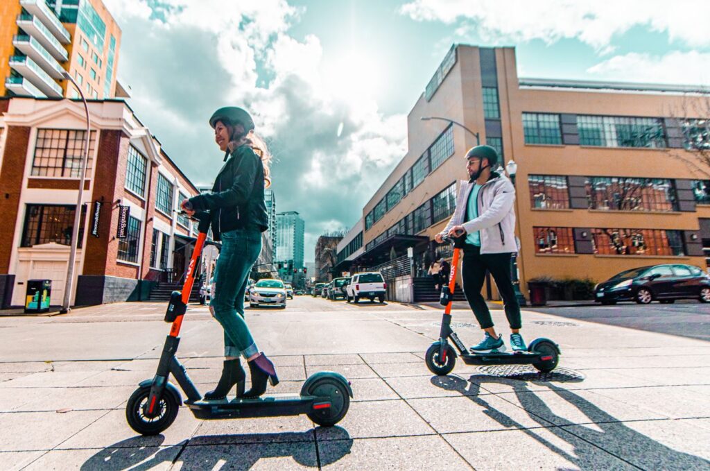 Two people riding spin scooters