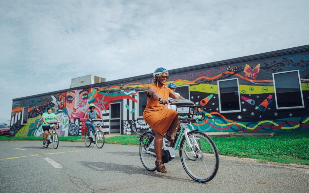 Woman bikes in front of bright mural